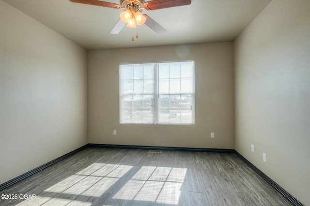 empty room with wood finished floors, a ceiling fan, and baseboards