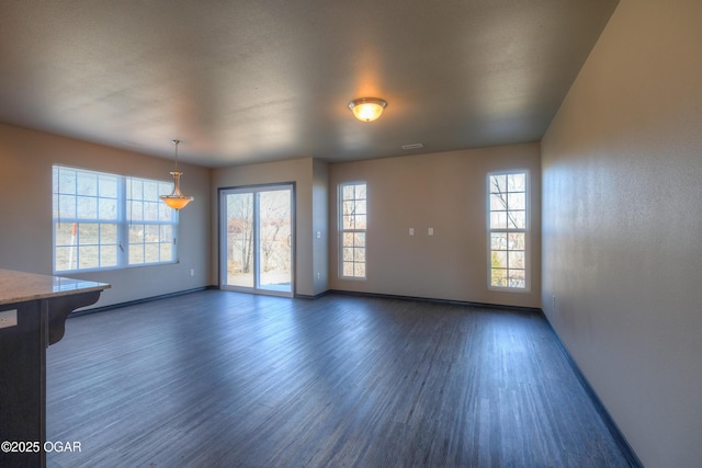 unfurnished room featuring baseboards and dark wood-type flooring