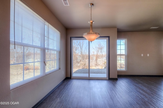 unfurnished dining area featuring dark wood finished floors and baseboards