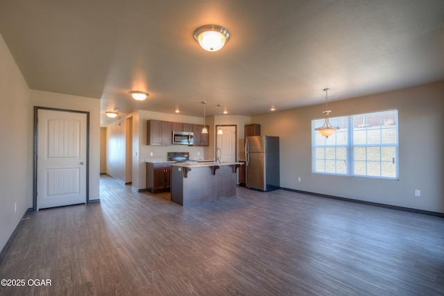 kitchen featuring stainless steel appliances, open floor plan, a kitchen breakfast bar, and dark wood-type flooring
