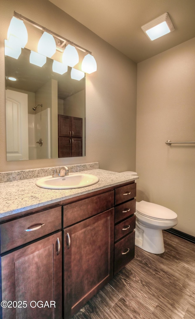 bathroom featuring wood finished floors, vanity, toilet, and a shower