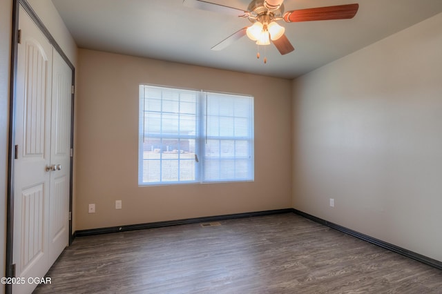 unfurnished bedroom with a closet, wood finished floors, baseboards, and ceiling fan