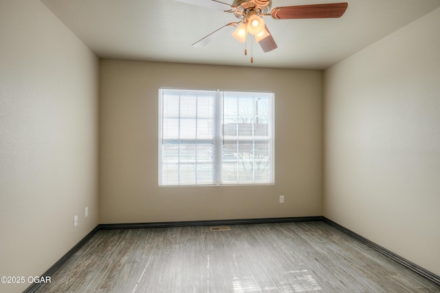 unfurnished room with ceiling fan, wood finished floors, and baseboards