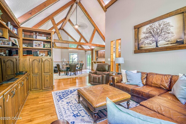 living area with beam ceiling, high vaulted ceiling, and light wood-style flooring