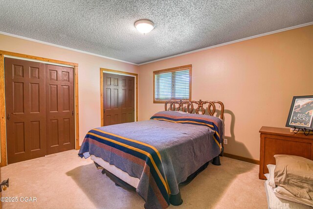carpeted bedroom featuring crown molding, two closets, and a textured ceiling