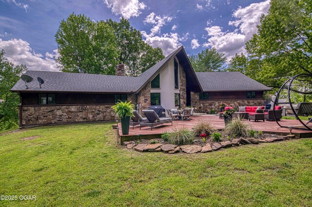 back of house with stone siding, an outdoor hangout area, a deck, and a yard