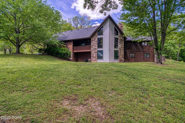 back of house featuring a chimney, stucco siding, a yard, and stone siding