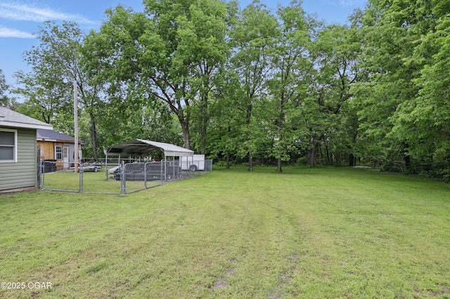 view of yard with a carport, a gate, and view of wooded area