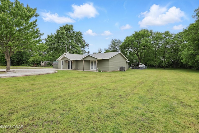ranch-style house featuring a front yard, french doors, driveway, and view of scattered trees