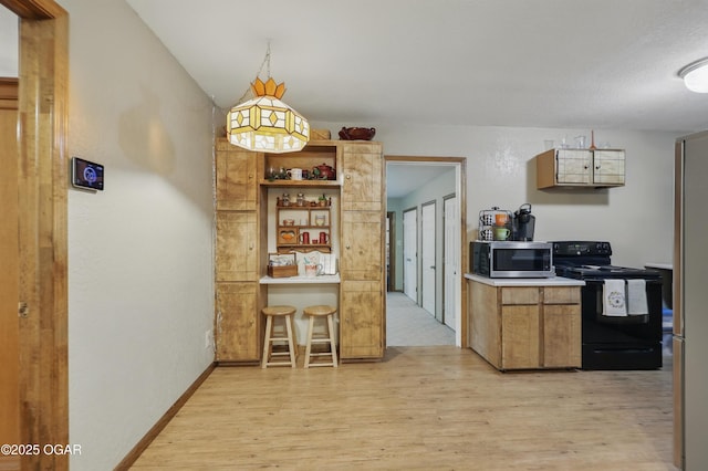 kitchen with stainless steel microwave, black / electric stove, light wood-style floors, and light countertops