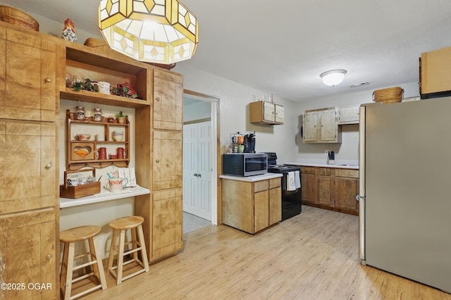 kitchen featuring stainless steel appliances, light wood-style floors, light countertops, and open shelves