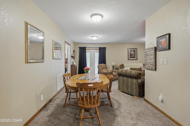 dining room featuring carpet floors, baseboards, and a textured ceiling