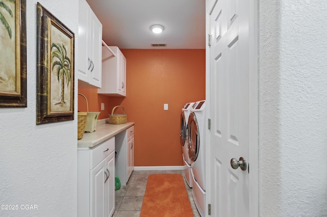 clothes washing area with independent washer and dryer, cabinet space, light tile patterned floors, and a textured wall