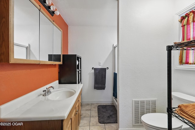 bathroom with toilet, tile patterned flooring, vanity, a shower with shower door, and baseboards