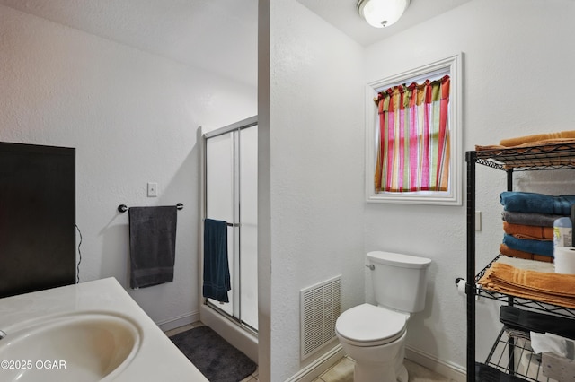 full bath featuring a sink, a shower stall, toilet, and baseboards