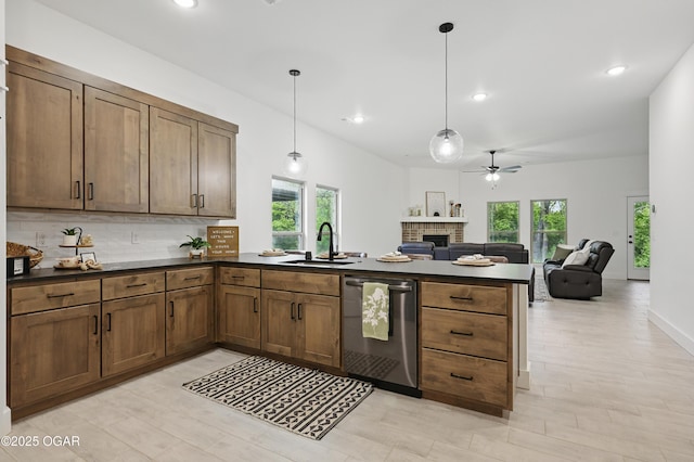 1318 Foundry Dr, Carthage, MO 64836 - kitchen featuring stainless steel dishwasher, a peninsula, dark countertops, a ceiling fan, and a brick fireplace
