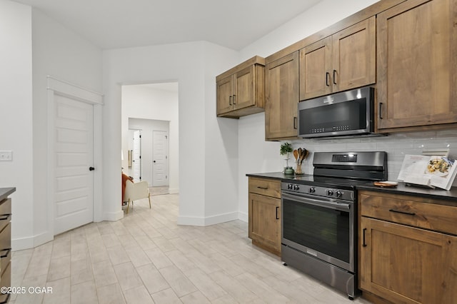 1318 Foundry Dr, Carthage, MO 64836 - kitchen with stainless steel appliances, dark countertops, baseboards, tasteful backsplash, and brown cabinetry