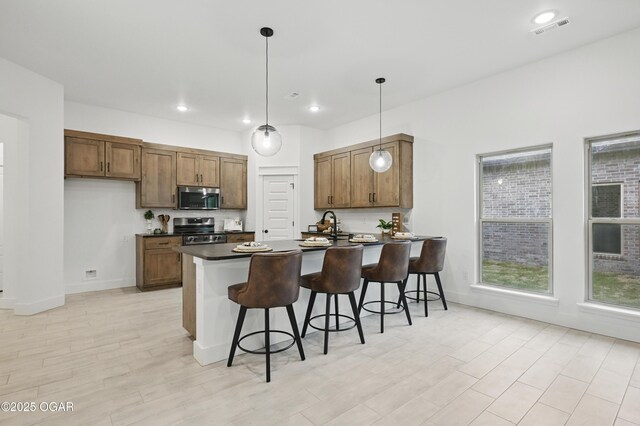 1318 Foundry Dr, Carthage, MO 64836 - kitchen featuring stainless steel appliances, dark countertops, a peninsula, a kitchen breakfast bar, and hanging light fixtures