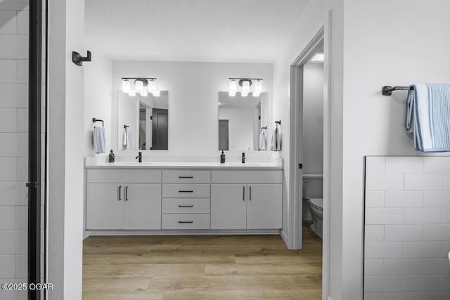 1528 N Edgemont Cir, Springfield, MO 65802 - bathroom featuring wood finished floors, toilet, double vanity, and a textured ceiling