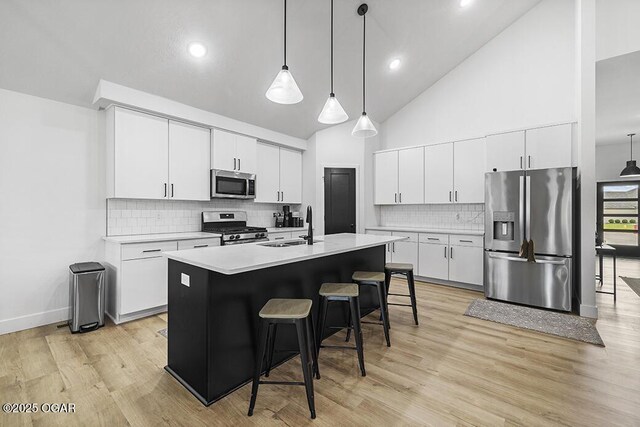1528 N Edgemont Cir, Springfield, MO 65802 - kitchen with stainless steel appliances, a sink, light countertops, a breakfast bar area, and decorative backsplash