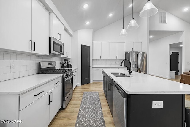 1528 N Edgemont Cir, Springfield, MO 65802 - kitchen with appliances with stainless steel finishes, a sink, light countertops, hanging light fixtures, and a kitchen island with sink