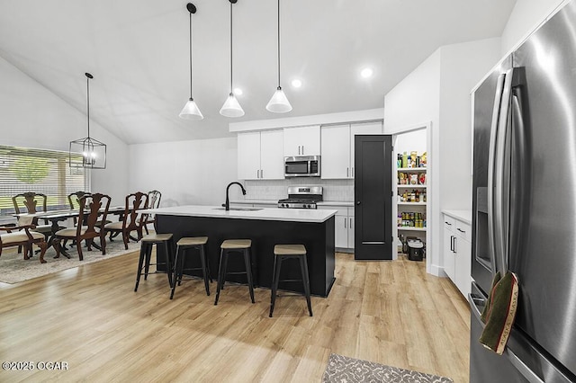 1528 N Edgemont Cir, Springfield, MO 65802 - kitchen featuring appliances with stainless steel finishes, a sink, a kitchen bar, light wood finished floors, and light countertops