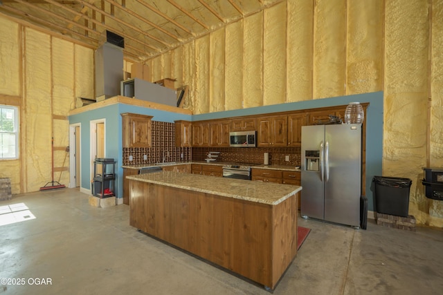 8740 County Road 241, Webb City, MO 64870 - kitchen featuring appliances with stainless steel finishes, concrete floors, a center island, a towering ceiling, and brown cabinets