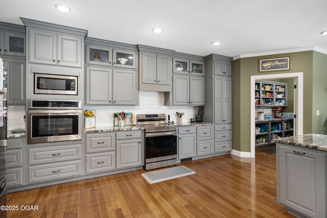 8740 County Road 241, Webb City, MO 64870 - kitchen with appliances with stainless steel finishes, gray cabinetry, backsplash, crown molding, and glass insert cabinets