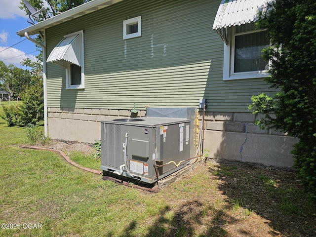 back of property featuring central air condition unit and a lawn