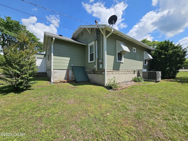 back of house with central AC unit and a yard