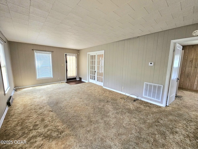 carpeted spare room featuring wooden walls and a smoke detector