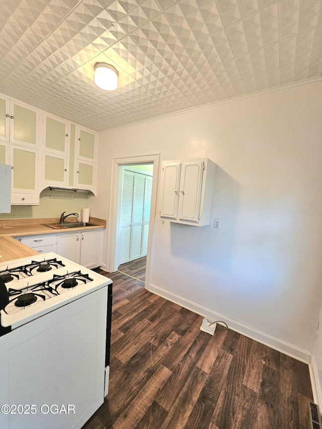 kitchen featuring white gas range, white cabinetry, a sink, glass insert cabinets, and light countertops