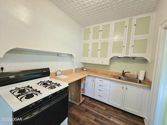 kitchen featuring gas range oven, a sink, dark wood-style flooring, light countertops, and glass insert cabinets