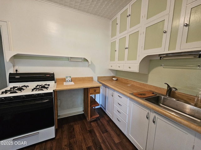 kitchen featuring gas stove, dark wood-type flooring, light countertops, white cabinetry, and crown molding