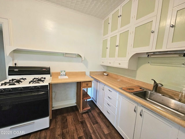 kitchen featuring range with gas cooktop, light countertops, dark wood-type flooring, glass insert cabinets, and a sink