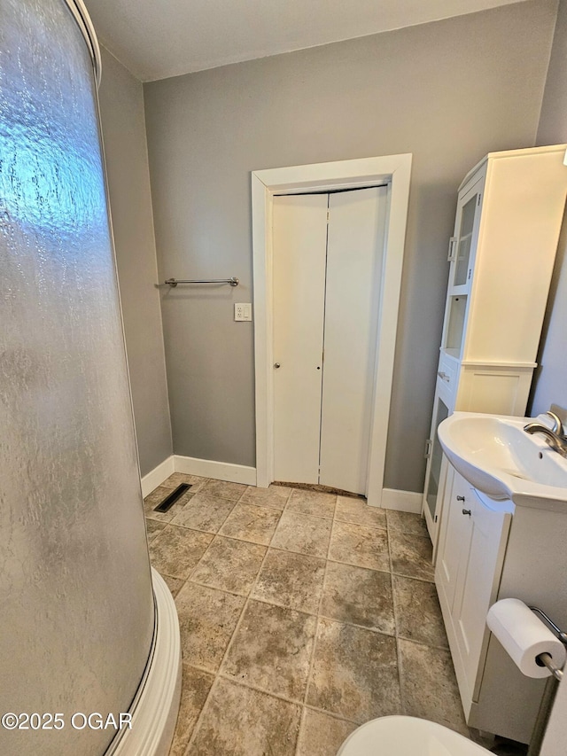 bathroom featuring stone finish flooring, vanity, and baseboards