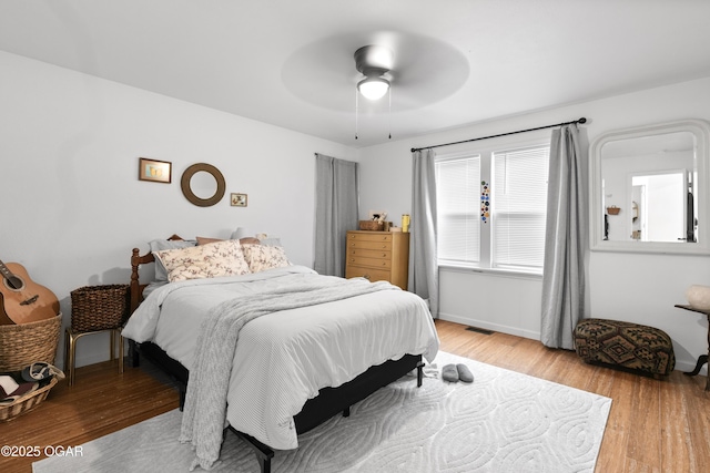 bedroom with light wood-style flooring, a ceiling fan, and baseboards