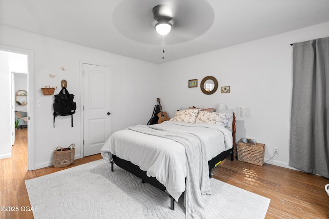 bedroom featuring wood finished floors, baseboards, a ceiling fan, and a closet