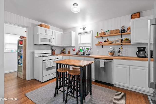 kitchen with white appliances, wood counters, a sink, and dark wood-style flooring