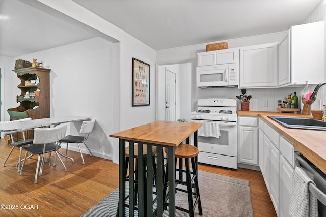 kitchen featuring white appliances, a sink, dark wood-type flooring, white cabinets, and wood counters
