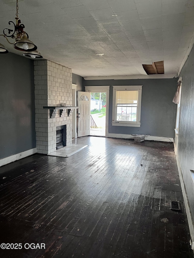 210 W 4th St, Webb City, MO 64870 - unfurnished living room featuring hardwood / wood-style floors, a brick fireplace, and a chandelier