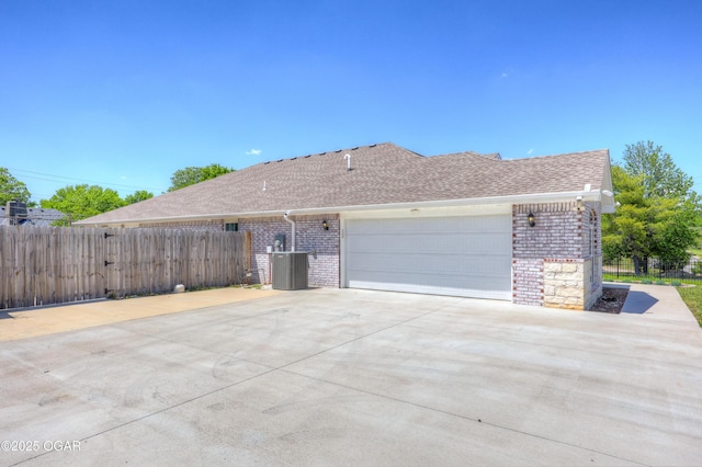 1020 S Florida Ave, Joplin, MO 64801 - view of side of property featuring brick siding, central AC unit, fence, a shingled roof, and concrete driveway
