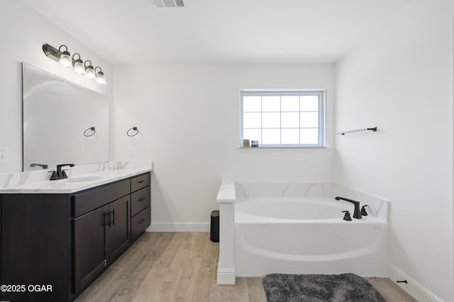 1020 S Florida Ave, Joplin, MO 64801 - bathroom with vanity, wood finished floors, a garden tub, and baseboards