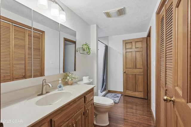 full bath with a closet, toilet, wood finished floors, vanity, and a textured ceiling