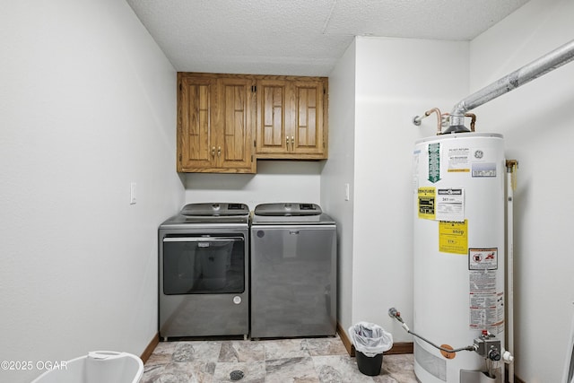 washroom featuring water heater, independent washer and dryer, cabinet space, baseboards, and a textured ceiling