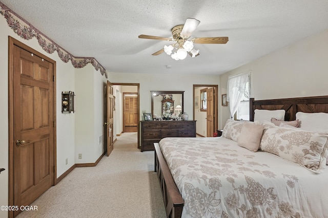 bedroom featuring light colored carpet, ceiling fan, a textured ceiling, and baseboards