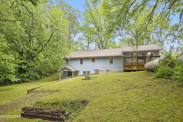 rear view of property with a wooden deck and a lawn