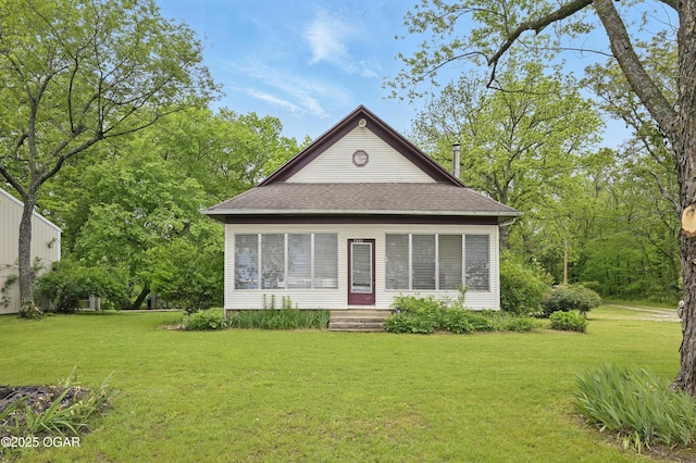 back of property with a yard and roof with shingles