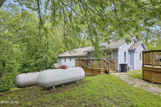 back of property featuring a deck, a yard, a shingled roof, and central AC