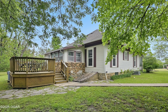 rear view of property with a deck, a yard, central AC, and a shingled roof